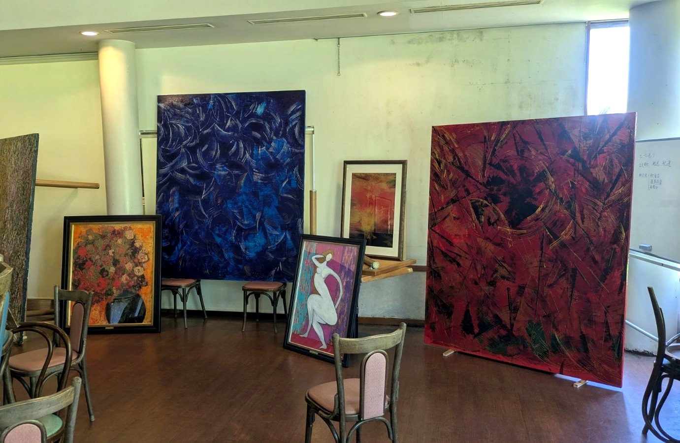 青や赤の大きな抽象画と花の絵画が並ぶ展示会場